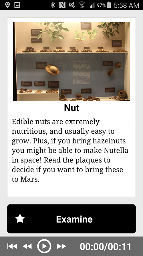 A screenshot from a phone of an app. At the top of the screenshot is a bar with various phone icons, including the battery indicator, the time (5:58), and the Bluetooth icon. Below that is a photo of a display case which has various nuts in piles, green leaves mounted on the wall, and many plaques mounted as well. Below the photo is the title "Nut." Below that title is the following text: "Edible nuts are extremely nutritious, and usually easy to grow. Plus, if you bring hazelnuts you might be able to make Nutella in space! Read the plaques to decide if you want to bring these to Mars." Below that text is a large black button with a star on it and the text "Examine." Below this button are the typical controls for a media player: go back to the beginning of the track, rewind, etc. The time for the playback reads 00:000/00:11.